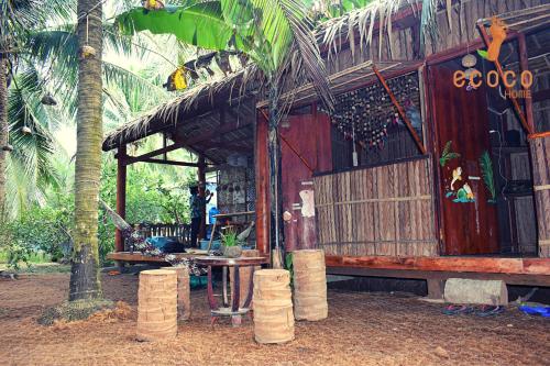 槟知Ecoco Homestay Mekong的小小屋,配有桌子和棕榈树