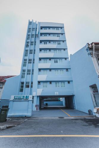 新加坡Hotel 81 Joy的一座高大的白色建筑,设有停车场