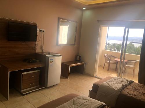 亚喀巴Al Deyafa Hotel的一间卧室配有一张床、一台电视和一个阳台