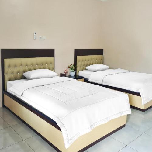 SampitRedDoorz @ Jalan Nyai Enat Sampit的两张睡床彼此相邻,位于一个房间里
