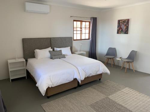 奥奇瓦龙戈Otjibamba Lodge的卧室设有一张白色大床和一扇窗户。