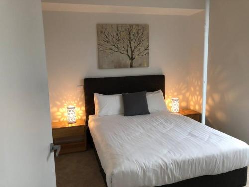 悉尼Beautiful Apartment in Chatswood的一间卧室配有一张带2个床头柜和2盏灯的床。