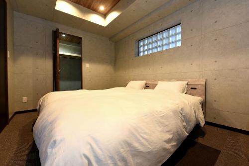 TsukisappuHills Garden 本通的卧室配有一张大白色床和窗户