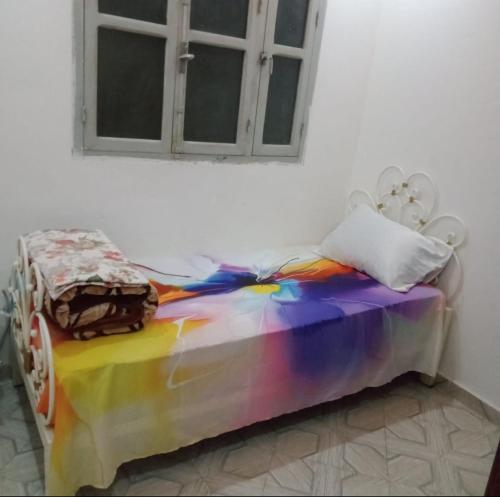 Bel Aroussiغرفة فردية خاصة للاناث的一张带彩虹色棉被的床