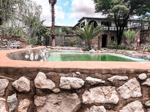KangNkisi Guesthouse的一座带石墙的庭院内的游泳池