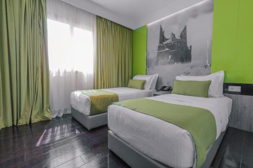 利雅德Super 8 Hotel Al Riyadh by Wyndham的绿墙客房内的两张床