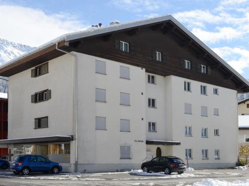库尔瓦尔登Apartment Seeli by Interhome的一座白色的大建筑,前面有汽车停放