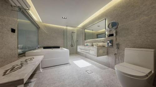 利雅德Madareem Hotel的带浴缸、卫生间和盥洗盆的浴室