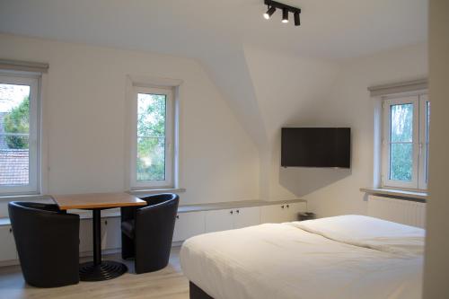 OostrozebekeHotel Swaenenburg的一间卧室配有一张床、一张桌子和一张桌子