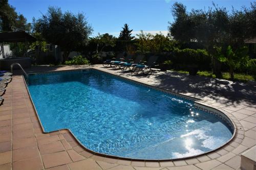 奥利维拉Villa Lluna Sitges 15 minutes drive from Sitges Swimming pool XXL 16 people的庭院内带椅子的大型游泳池