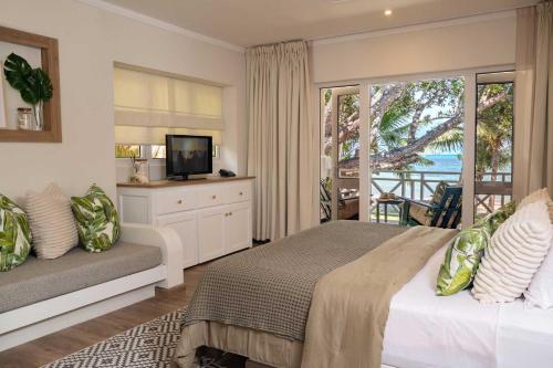 普拉兰大安塞区印度洋旅舍的一间卧室设有一张床、一台电视和一个阳台。