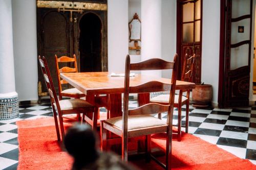 丹吉尔The Riad Hostel Tangier的一间带木桌和椅子的用餐室