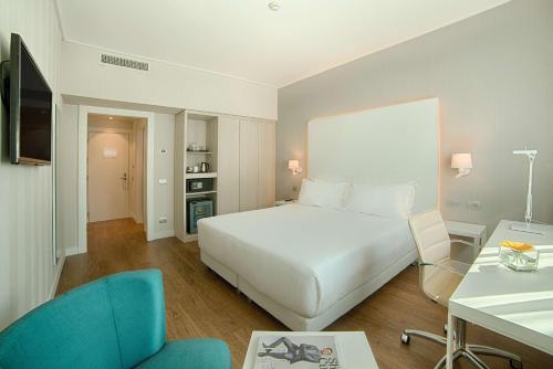 都灵NH都灵中心酒店的酒店客房带一张床、一张桌子和椅子