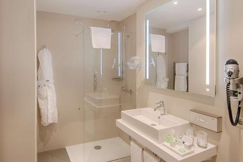 都灵NH都灵中心酒店的白色的浴室设有水槽和淋浴。