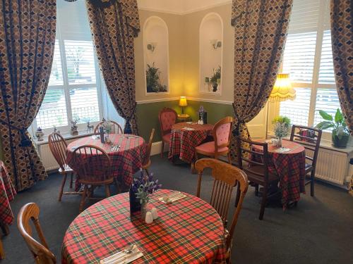 卡莱尔对角地旅馆的餐厅设有两张桌子和椅子,配有红色的格子桌