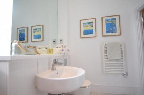 奇切斯特Beautiful flat in luxury Graylingwell development的白色的浴室设有水槽,墙上挂有一些图片