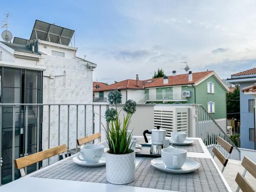 皮内托Homiday - Residenza Caravelle的阳台上的桌子上放有杯子和碟子