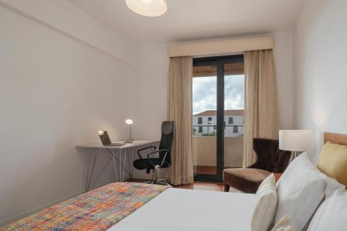 丰沙尔Casa Sta Clara的配有一张床、一张书桌和一扇窗户的酒店客房