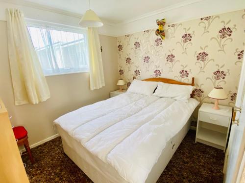 大雅茅斯Quiet and Comfy 2- bedroom Holiday Chalet, walk to the beach, Norfolk的卧室配有白色的床和窗户。