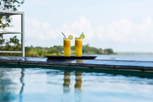 阿鲁甘湾Oruwa Boutique Villas的水边的桌子上放着两杯饮料的游泳池