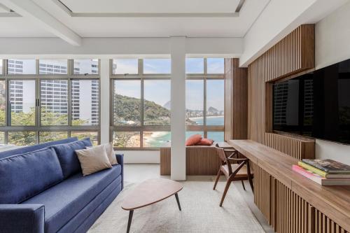 里约热内卢Beach Loft next to the Sheraton Leblon的客厅设有蓝色的沙发和大窗户