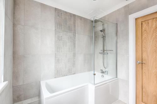 马伯斯3-bed in Mumbles with free parking & sea views的带淋浴和白色浴缸的浴室