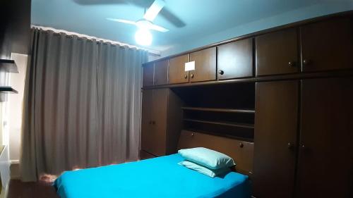 圣维森特岛Apto acochegante com Praia e lazer的一间卧室配有一张蓝色的床和木制橱柜。