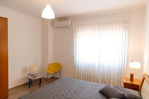 阿马兰特Twin House - Amarante的一间卧室配有床、黄椅和窗户