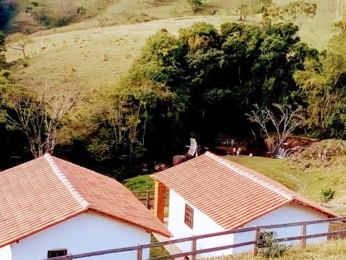 布埃诺布兰当Chalés Cachoeira Cafundó的两座房子的屋顶,后方是一座山丘