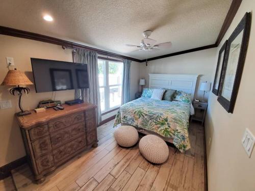 可可比奇Hawaiian Cottage - Heated Pool Walk to the Beach的一间卧室配有一张床和一台平面电视