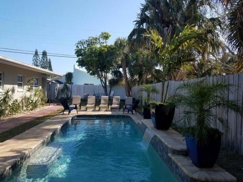 可可比奇Hawaiian Cottage - Heated Pool Walk to the Beach的庭院内的游泳池,带椅子和树木
