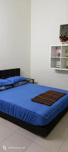 昔加末Rawyna homestay segamat的一间卧室配有一张带蓝色毯子和架子的床