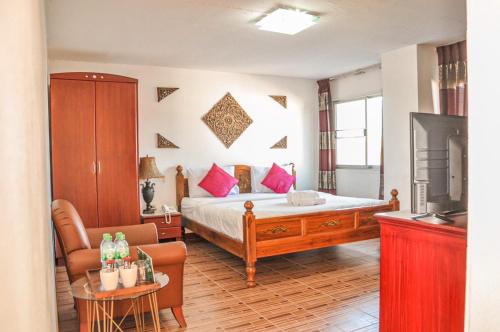 南邦南邦雷根特旅舍的一间卧室配有一张床、一把椅子和电视。