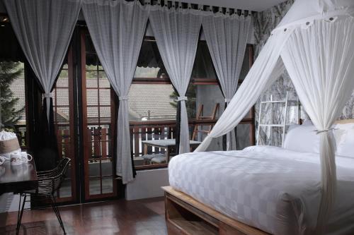 不拉士打宜卡朗乌鲁酒店的一间卧室配有带窗帘的床和阳台