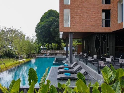 那空拍侬府VELA DHI Nakhon Phanom的一座带躺椅的游泳池和一座建筑