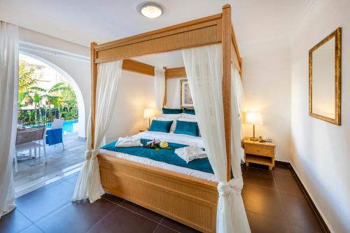 科斯镇培立迪斯家庭度假村的一间卧室设有一张天蓬床和一个阳台