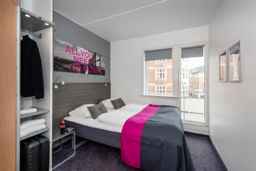 哥本哈根卡宾城市酒店的一间卧室配有一张床铺,床上铺有粉色毯子