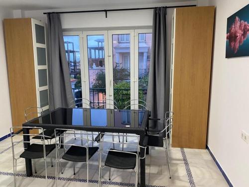 圣玛丽亚港Apartamento Medina Puerto Sherry的窗户客房内的一张黑桌子和椅子