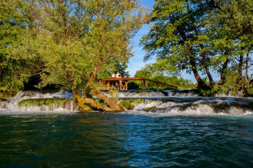 比哈奇Holiday Homes Pozitiva的一座河上的桥,有瀑布