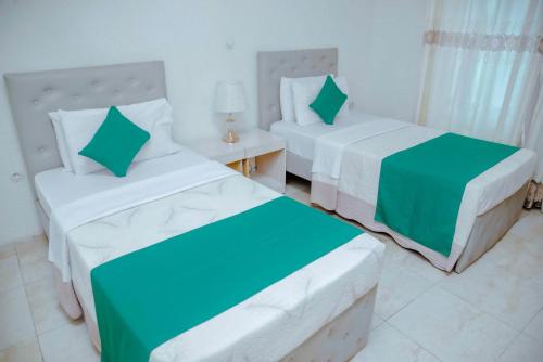 基加利Room in BB - Martin Aviator Hotel的一间卧室配有两张床,还有一个床头柜和一张桌子