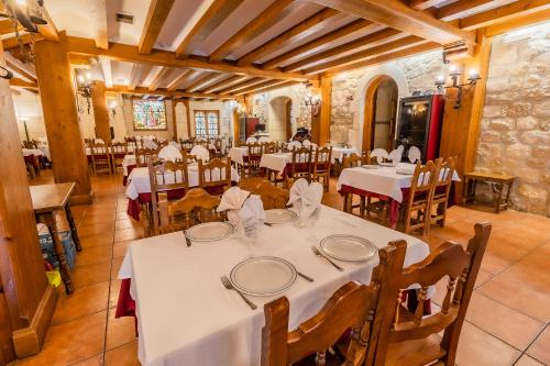 桑托多明戈德锡洛斯桑托多明戈德西洛斯旅馆的用餐室配有白色的桌子和木椅