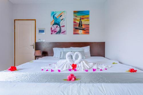 达拉万度Violet Inn Hotel的一张白色的床,上面有两条天鹅绒毛巾和鲜花