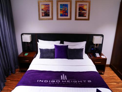 拉合尔Indigo Heights Hotel & Suites的一间卧室配有一张带紫色枕头的大床