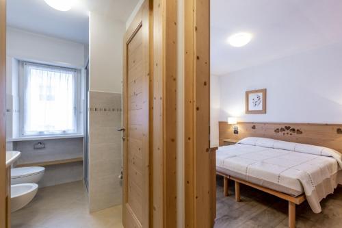 坎皮泰洛迪法萨Stella Alpina的一间卧室设有一张床、一个卫生间和一个水槽