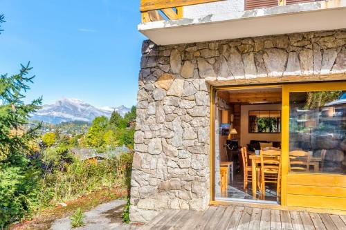 梅杰夫Charming apartment in a chalet with big terrasse and beautiful view的石屋,设有玻璃门和桌椅