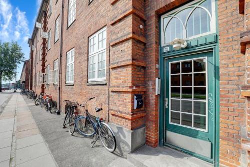 哥本哈根Cosy room in residential part of Copenhagen, with free street parking and shared bathroom的停在砖砌建筑一侧的一群自行车