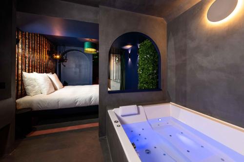 罗科福尔拉贝杜勒Minamina, chambre avec jacuzzi privatif的一间带浴缸的浴室和一张位于客房内的床