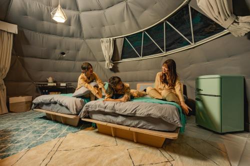 仓敷OKAYAMA GLAMPING SORANIA - Vacation STAY 73195v的三个妇女坐在帐篷里的床上