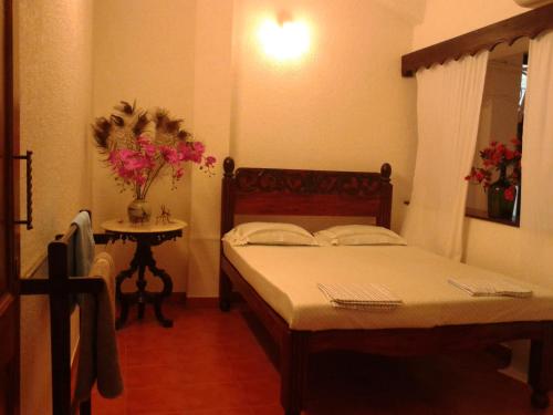 帕纳吉Afonso Guest House的一间卧室配有两张床和一张鲜花桌