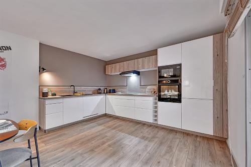 阿维尼翁Aux MARCHES DU PALAIS - AC CLIM - SPACIEUX - TERRASSE - WIFI的厨房铺有木地板,配有白色橱柜。